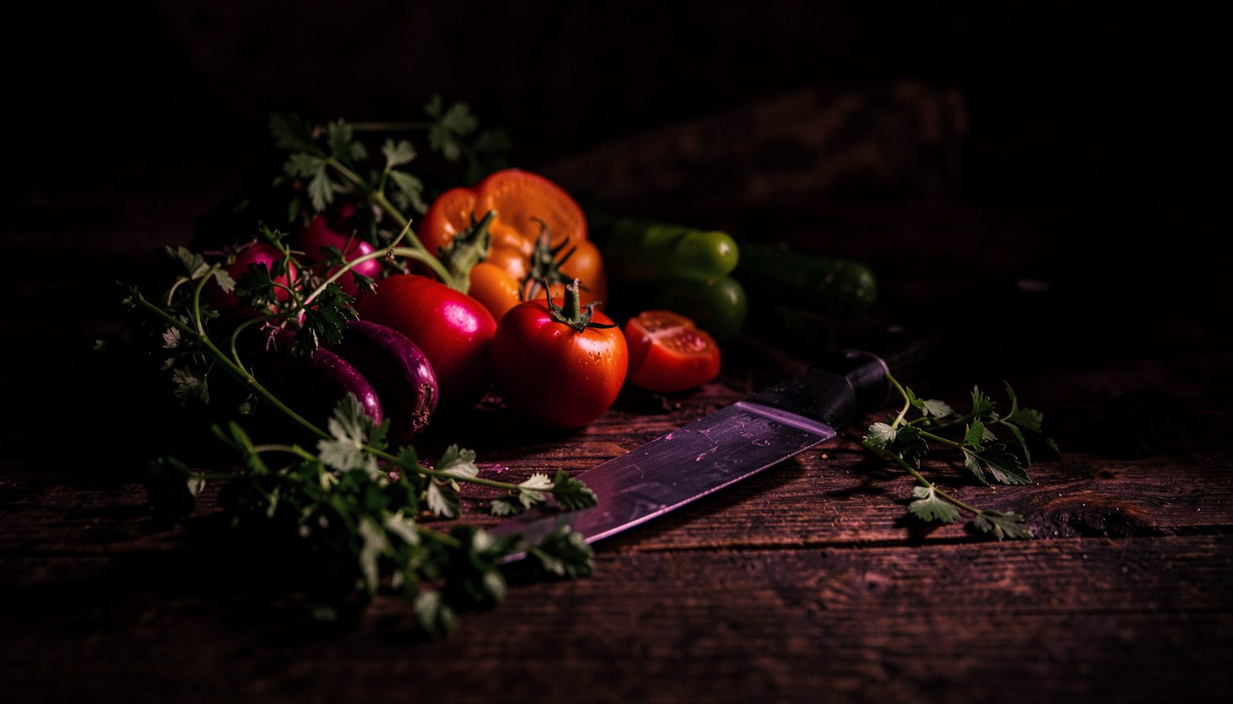 Plan de travail en bois sombre avec des légumes frais, herbes aromatiques et un couteau, éclairage tamisé et chaleureux