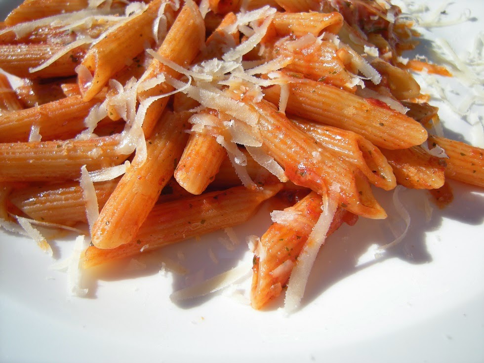 Gros plan de penne dans une sauce tomate avec fromage râpé, sur assiette blanche