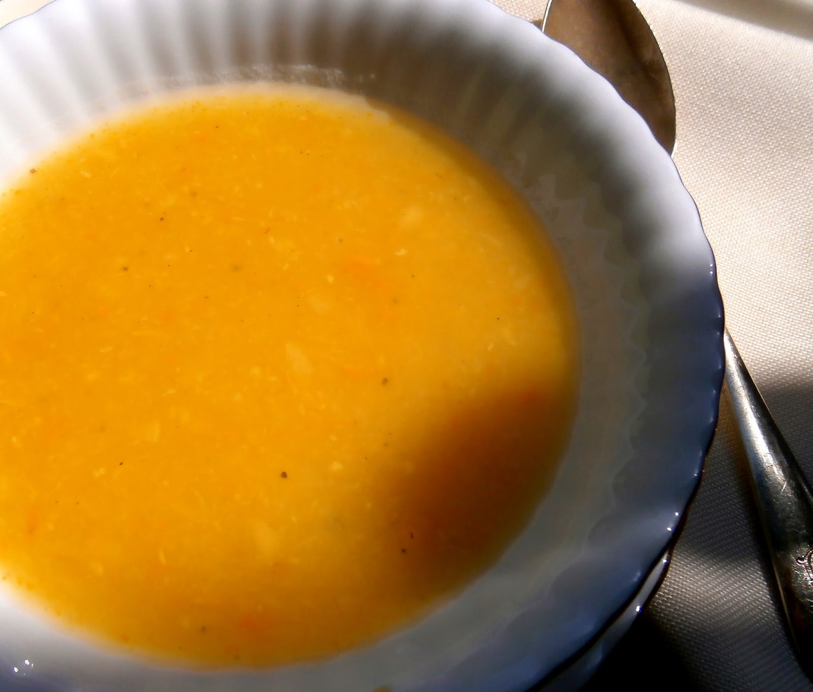 Gros plan d'une soupe lisse orange dans un bol blanc avec une cuillère